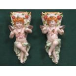 PAIR OF CONTINENTAL HANDPAINTED AND GILDED RELIEF DECORATED CHERUB FORM WALL POCKETS (AT FAULT)