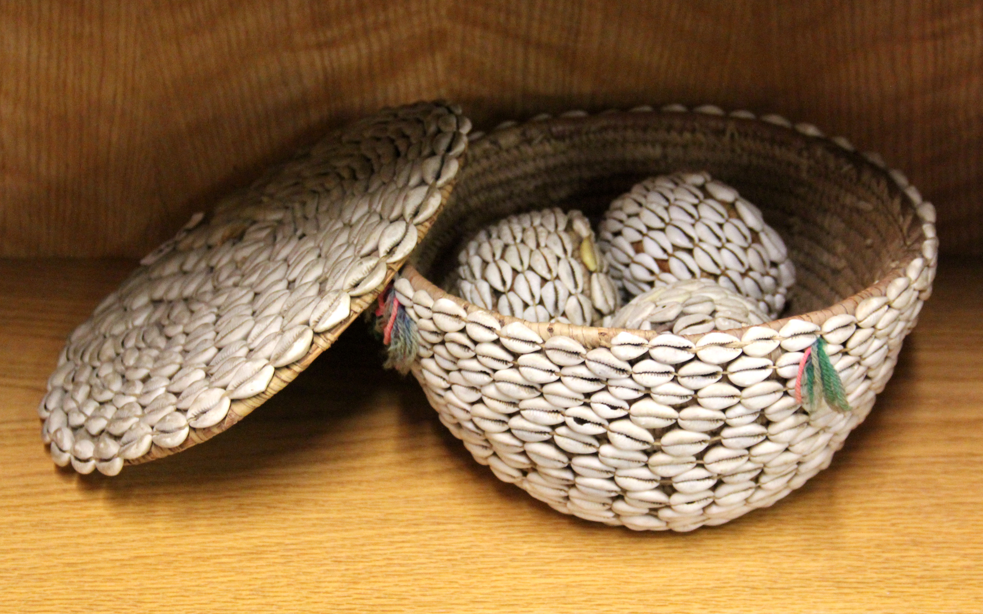 An interesting cowrie shell decorated tribal basket and three similar cowrie decorated balls.