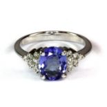 An 18ct white gold ring set with an oval cut tanzanite and diamond set shoulders (N.5).