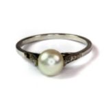 A white metal (tested minimum 9ct gold) pearl ring with diamond set shoulders (S).