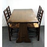 An oak dining table and four rush seated ladder backed chairs, in the Ercol style.