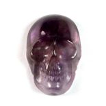 An unmounted 14.5ct carved amethyst in the shape of a skull, L. 2.2cm.