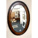 A 1930's oval oak framed hanging wall mirror, 53cm x 82cm.