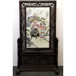 An early 20th century Chinese hand painted porcelain panel in a free standing wooden screen frame,