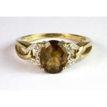 A 9ct yellow gold ring set with a faceted orange topaz and diamond set shoulders (P.5).