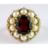 A large yellow metal (tested minimum 9ct gold) ring set with an oval cut garnet surrounded by pearls