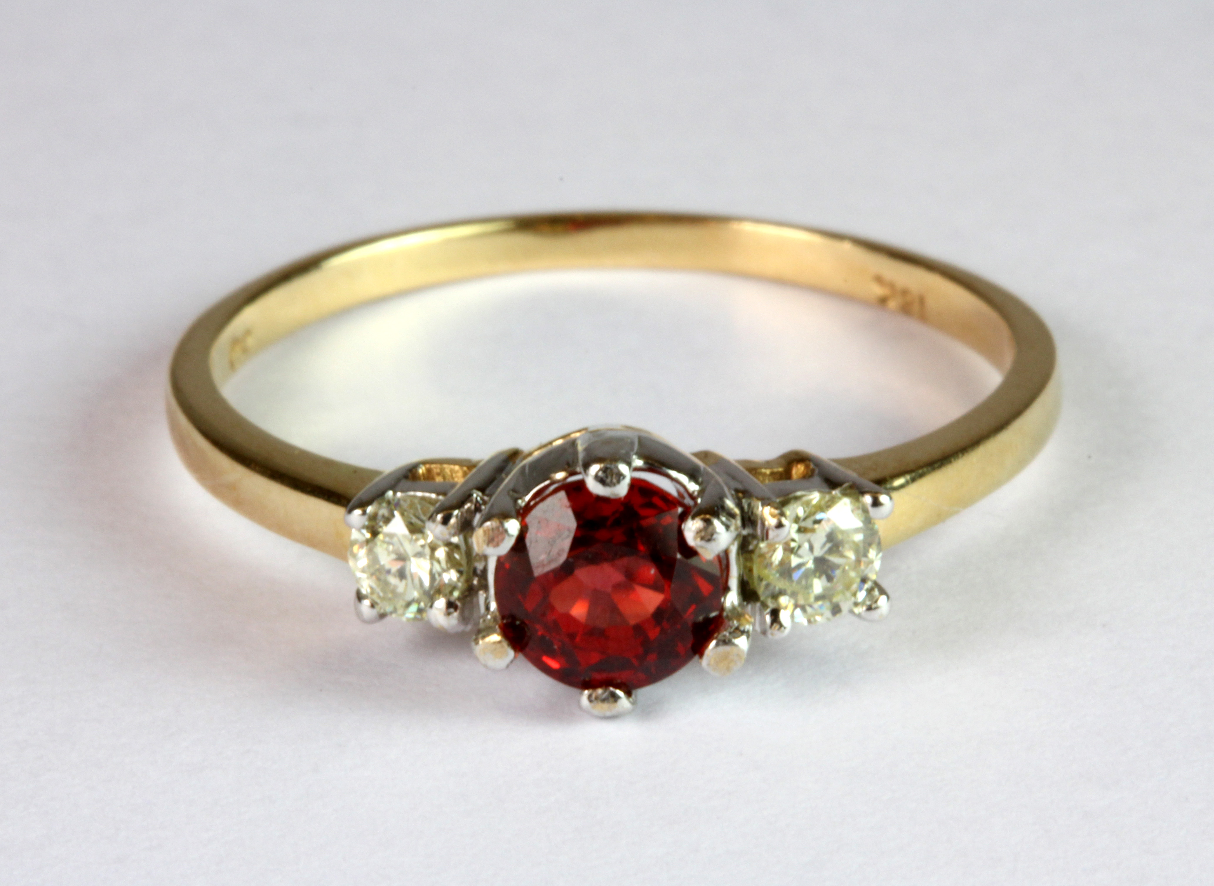 An 18ct yellow and white gold (stamped 18k) ring set with a brilliant cut ruby flanked by