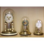 Three anniversary clocks, each under domes, Largest 30cm.