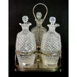 A silver plated and cut glass three bottle Tantalus.