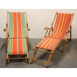 A pair of vintage folding hardwood and canvas deckchairs, with fold out supports.