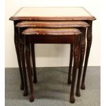 A nest of three leather inset mahogany coffee tables.