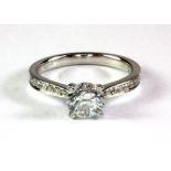 An 18ct white gold (stamped 750) solitaire ring with diamond set shoulders, centre diamond approx.