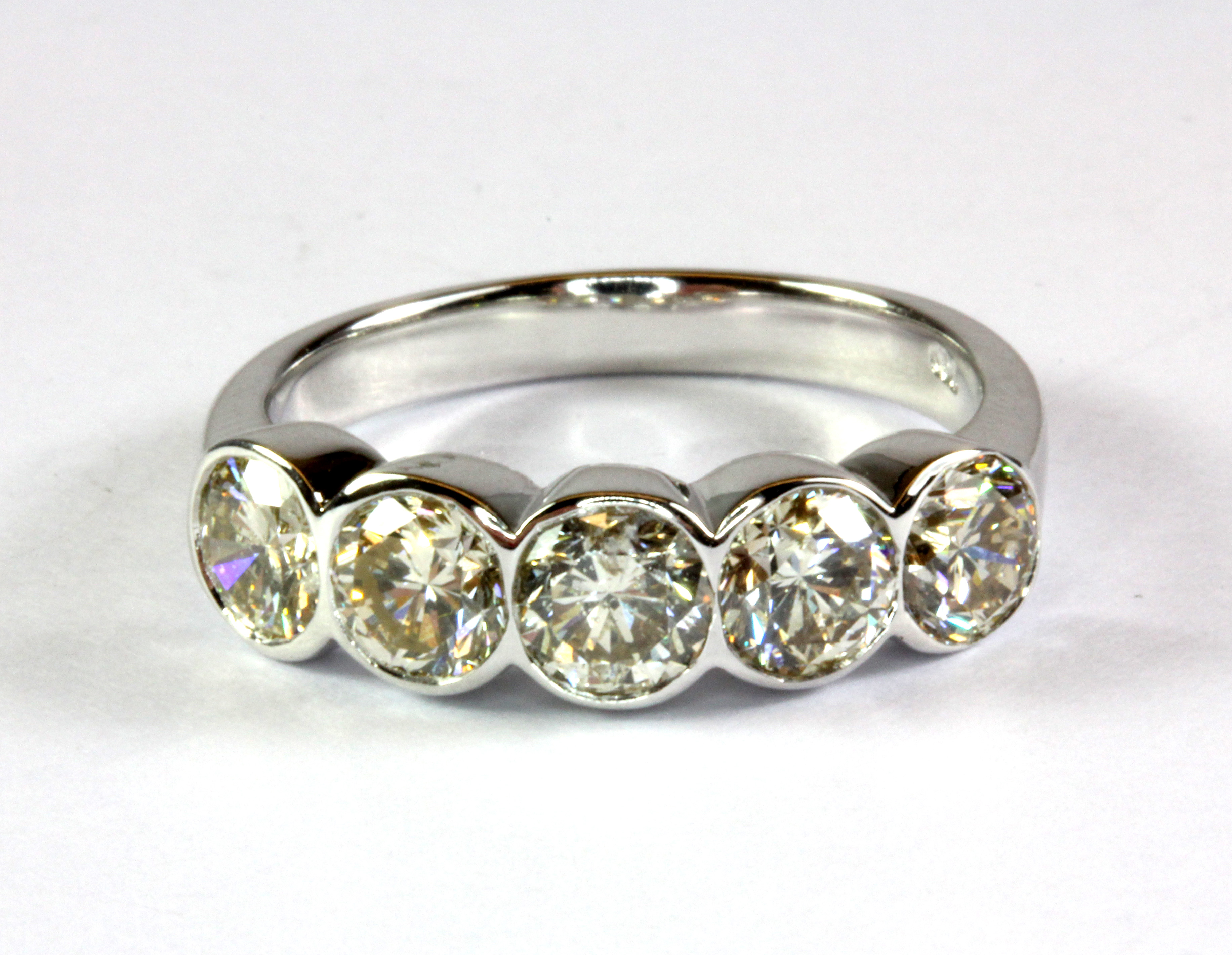 An 18ct white gold ring (stamped 750) set with five brilliant cut diamonds in a rub over setting (