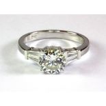 An 18ct white gold (stamped 750) ring set with a 1.30ct brilliant cut diamond with baguette cut