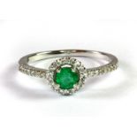 A 9ct white gold emerald and diamond halo ring with diamond set shoulders (N).