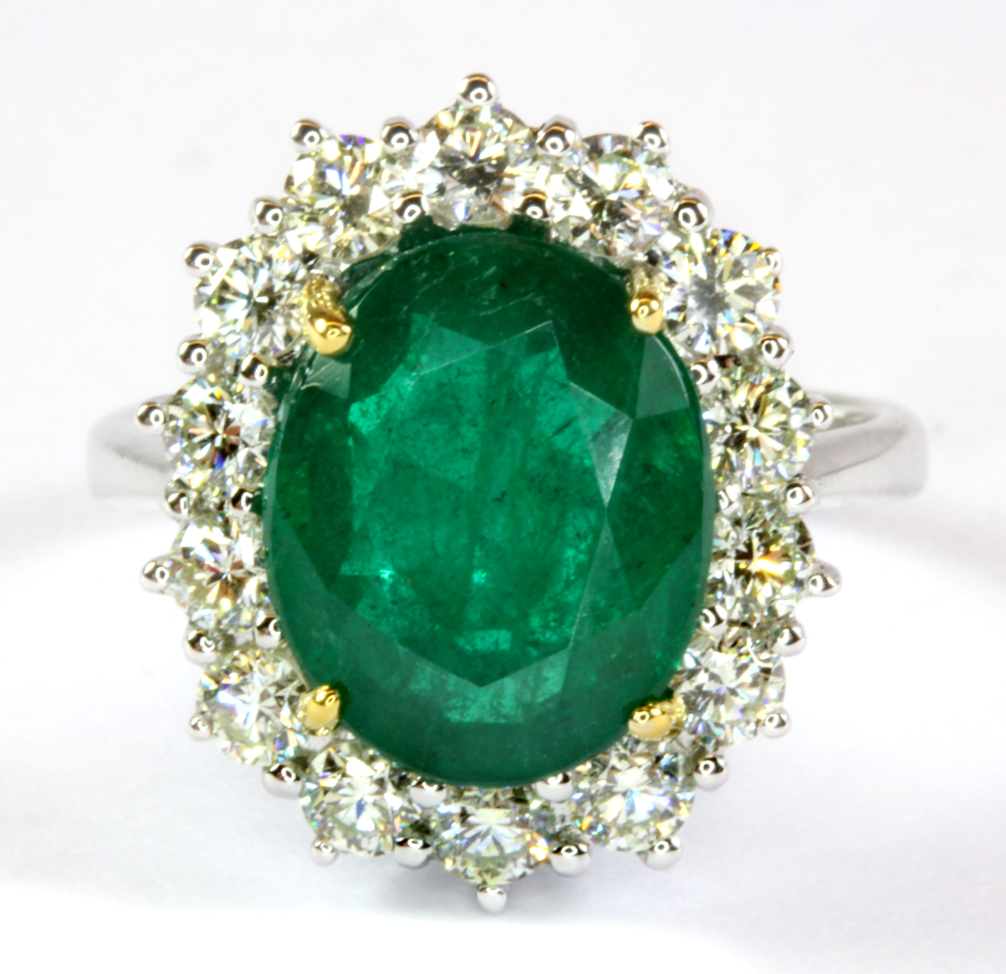 An 18ct white gold (stamped 750) ring set with an emerald (4.94ct) surrounded by diamonds (1.16ct)(