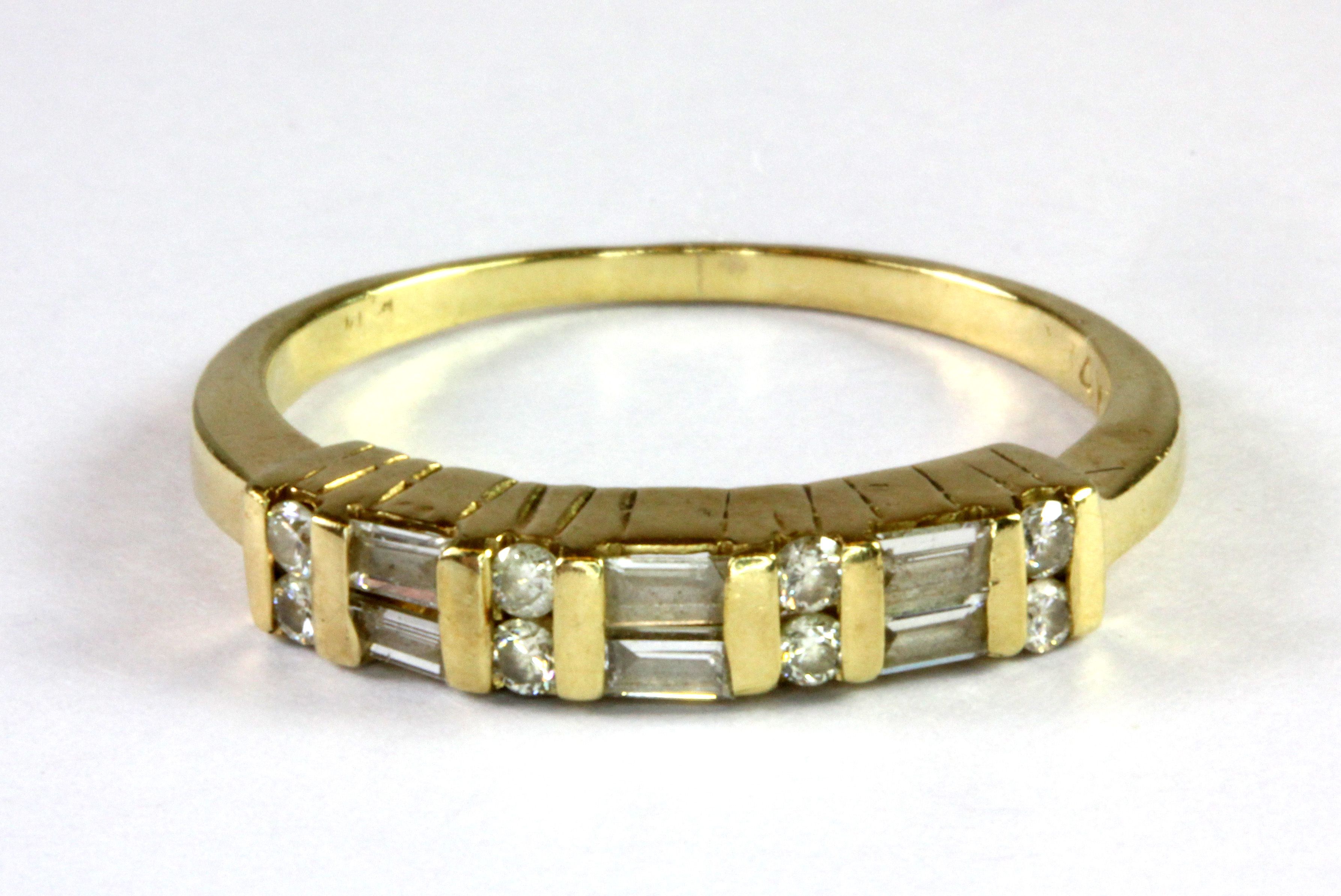 A 14ct yellow gold (stamped 14k) half eternity ring set with baguette and brilliant cut diamonds (