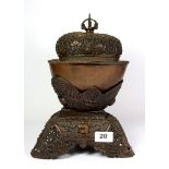 An early 20th century Tibetan hammered copper skull shaped bowl and cover with stand, H. 30cm (a/f