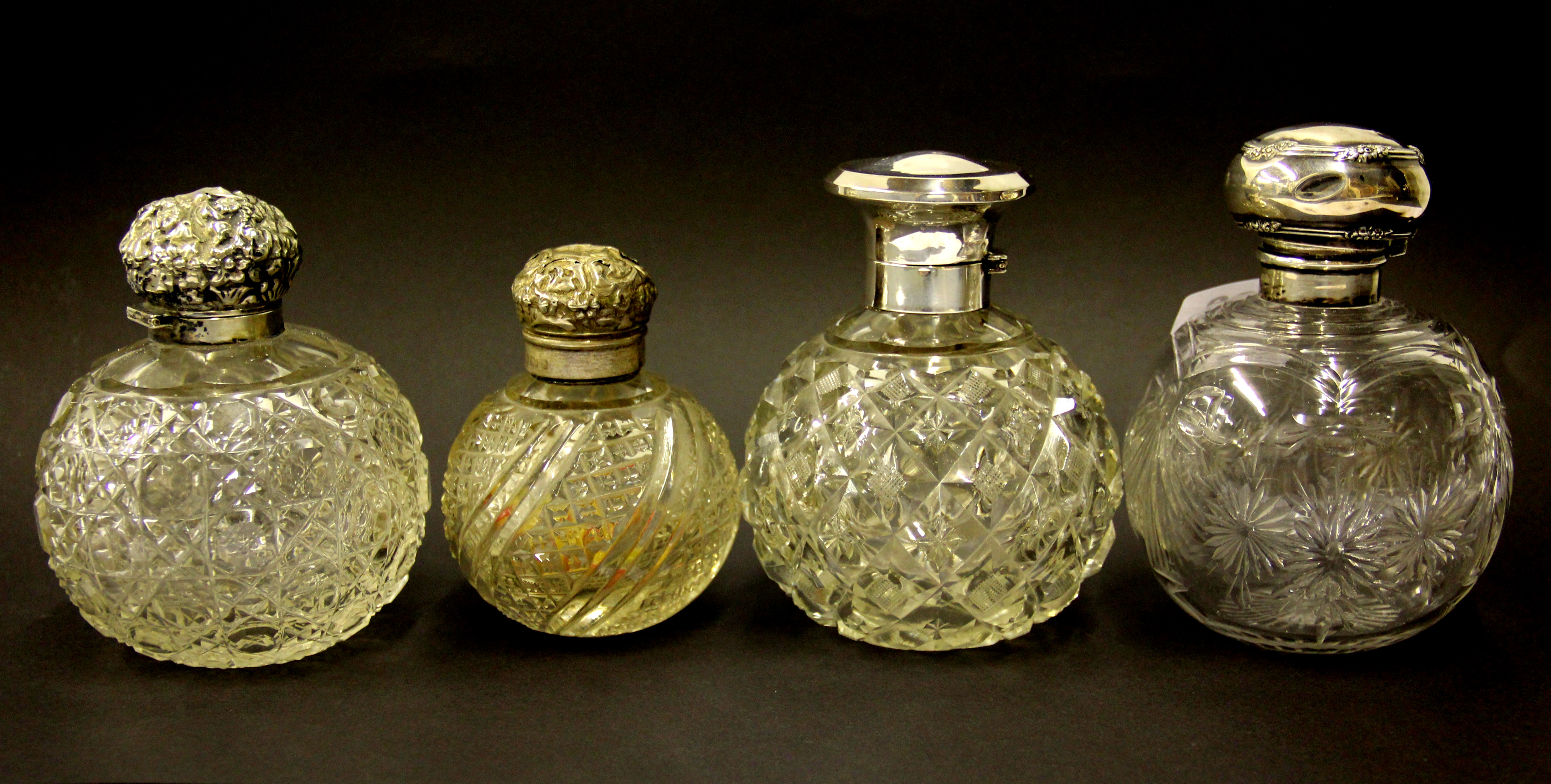 Four silver topped cut glass perfume bottles. Tallest 13.cms.