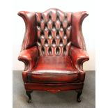 A button backed ox blood leather wing backed club chair. H. 107cms.