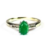 A 9ct white gold (stamped 375) ring set with carved emerald and diamond set shoulders, (L.5).