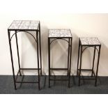 A set of three graduated tile topped iron tables, tallest 74cms.
