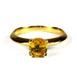 An 18ct yellow gold (stamped 750) ring set with an oval cut yellow sapphire, (M).