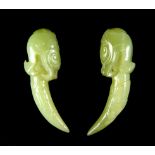 An unusual pair of Chinese carved jadeite jade amulets of tigers heads holding a tiger's claw, L.