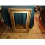 A gilt composite picture frame with relief moulded decoration (78cm x 58cm).