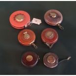 A collection of six early 20th century and later leather and metalware cased tape measures,