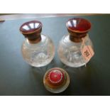 A pair of crystal cut glass scent bottles, each with silver and red enamel mounts,