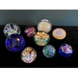A collection of nine glass paperweights, to include examples by Caithness, Langham Glass and others.