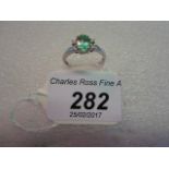 A single stone ring, the oval cut green stone with two diamonds to each side,