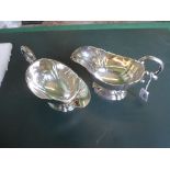 A pair of George V silver sauce boats, having scroll handle on pedestal foot,