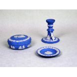 Three items of Wedgwood blue Jasperware, to include: candlestick, covered dish and pin dish.