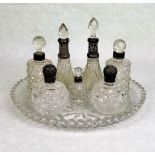 A circular crystal glass tray, together with seven crystal dressing table jars,