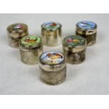 A set of six silver cylindrical pill boxes, each having hand painted enamel cover,
