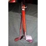 A collection of five golf clubs, early 20th century and later, each with wooden shafts,