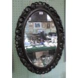 An oak framed oval wall mirror, the bevelled edge glass measuring 65cm x 39cm.
