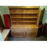 A large pine kitchen dresser, having three plate shelves over two drawers and two cupboard doors,
