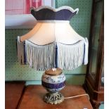 A late Victorian ceramic and gilt metal table lamp in the aesthetic manner, with tassled shade,