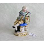 A Meissen figure of a seated finely dressed gentleman, a bunch of grapes beneath his chair,