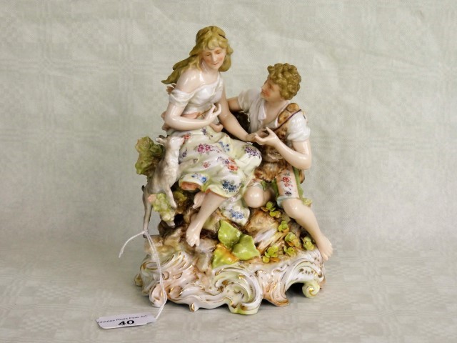 A 19th century porcelain figure group, seated couple with a lamb, having applied floral decoration,