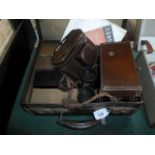 An early 20th century brown leather suitcase containing a quantity of camera equipment,