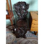 A 20th century carved oak hall chair, having stylized figures and leaf decoration.