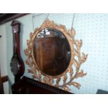 A circular gilt framed wall mirror, having stylized leaf and berry decoration,