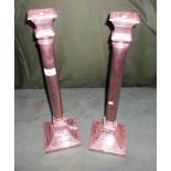 A pair of tall white metal candlesticks of columnar form on stepped square base, 48cm.