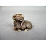 A Japanese carved bone netsuke depicting a recumbent goat with head turned to the left, 4.5cm wide.