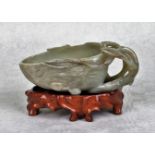 A Chinese carved jade libation cup, the handle formed as stylized branches and leaves,