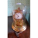 An early 20th century brass anniversary clock under fitted glass dome,